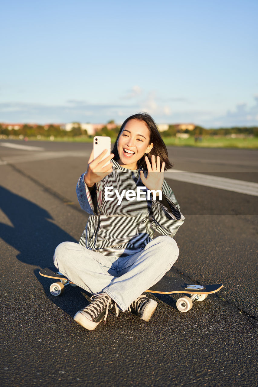 side view of young woman sitting on road