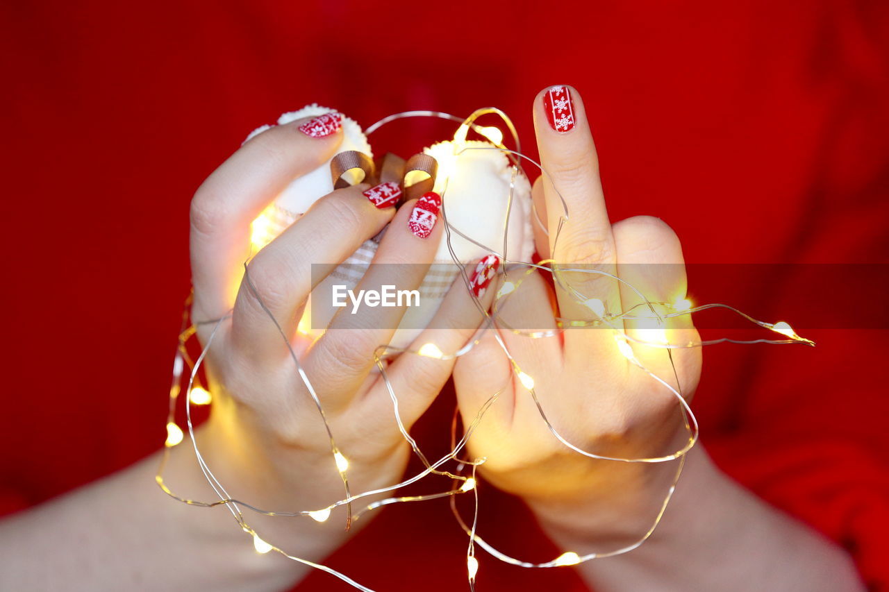 Midsection of woman holding illuminated string light with heart shape decoration