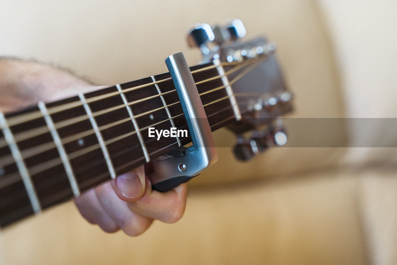 Cropped hand of man preparing guitar in home