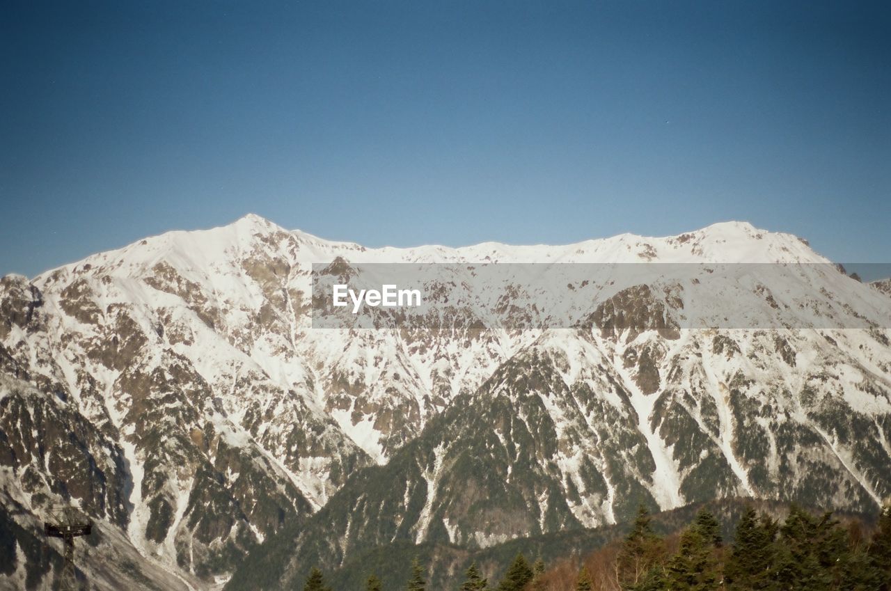 low angle view of snowcapped mountains against clear blue sky