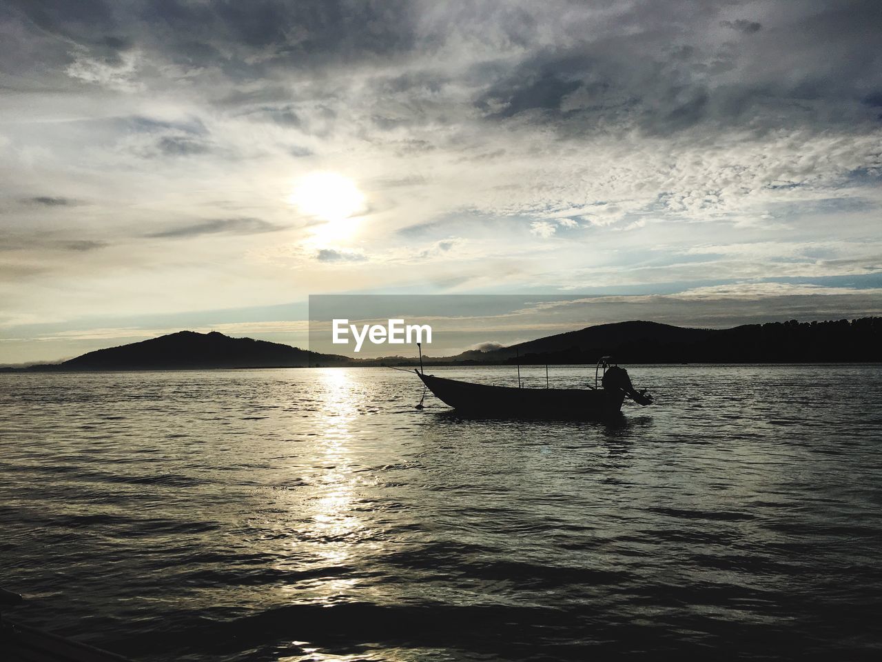 Silhouette boat in lake against sky during sunset