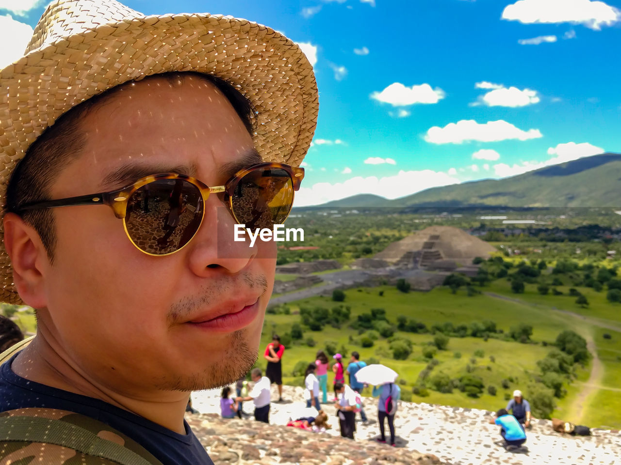 PORTRAIT OF MAN WITH SUNGLASSES AGAINST MOUNTAINS