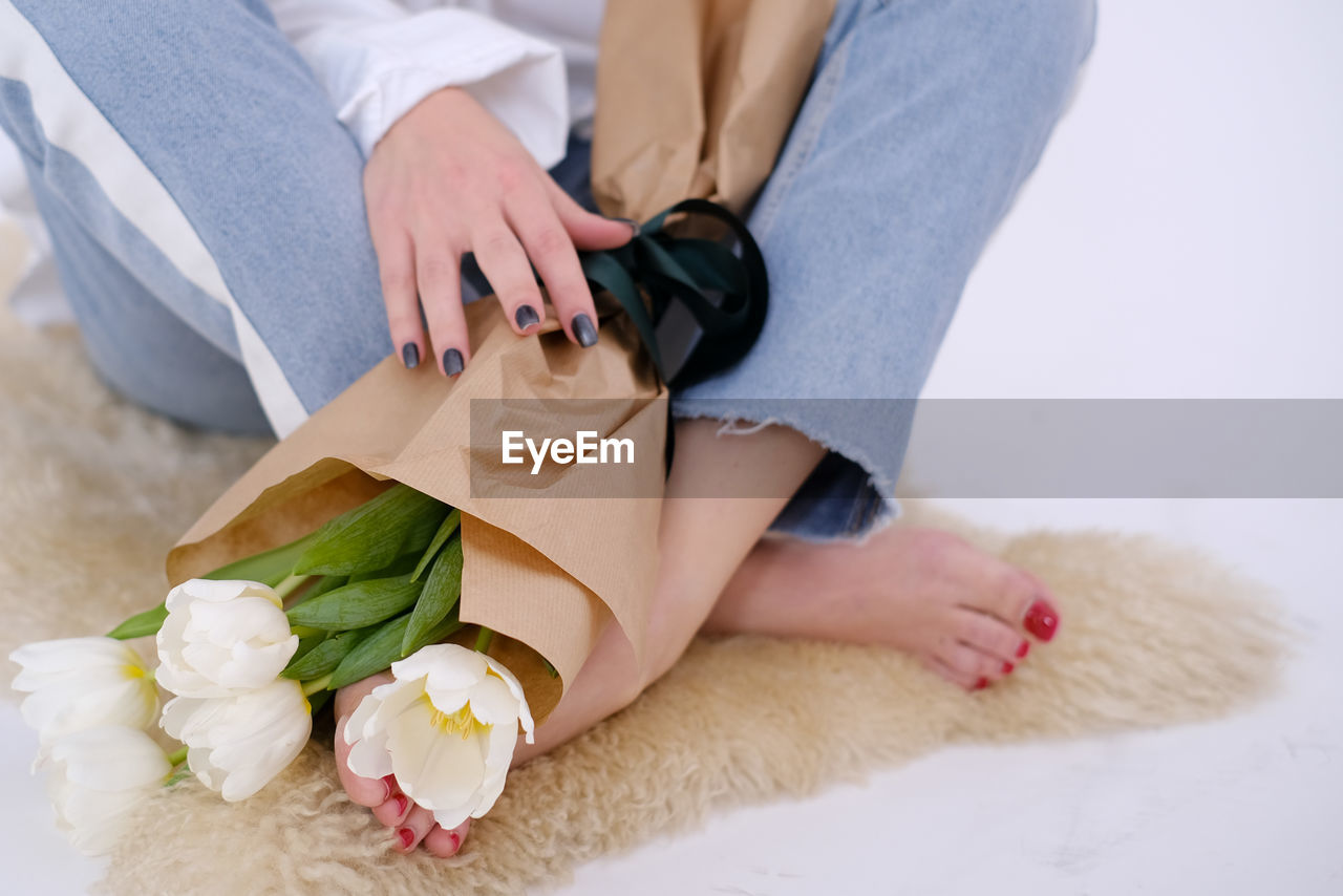 adult, women, one person, indoors, sitting, flower, female, holding, clothing, young adult, lifestyles, flowering plant, plant, wedding dress, low section, spring, relaxation, nature, hand, footwear, human leg, midsection, bride, casual clothing, love, rose, close-up, fashion, newlywed, positive emotion, furniture