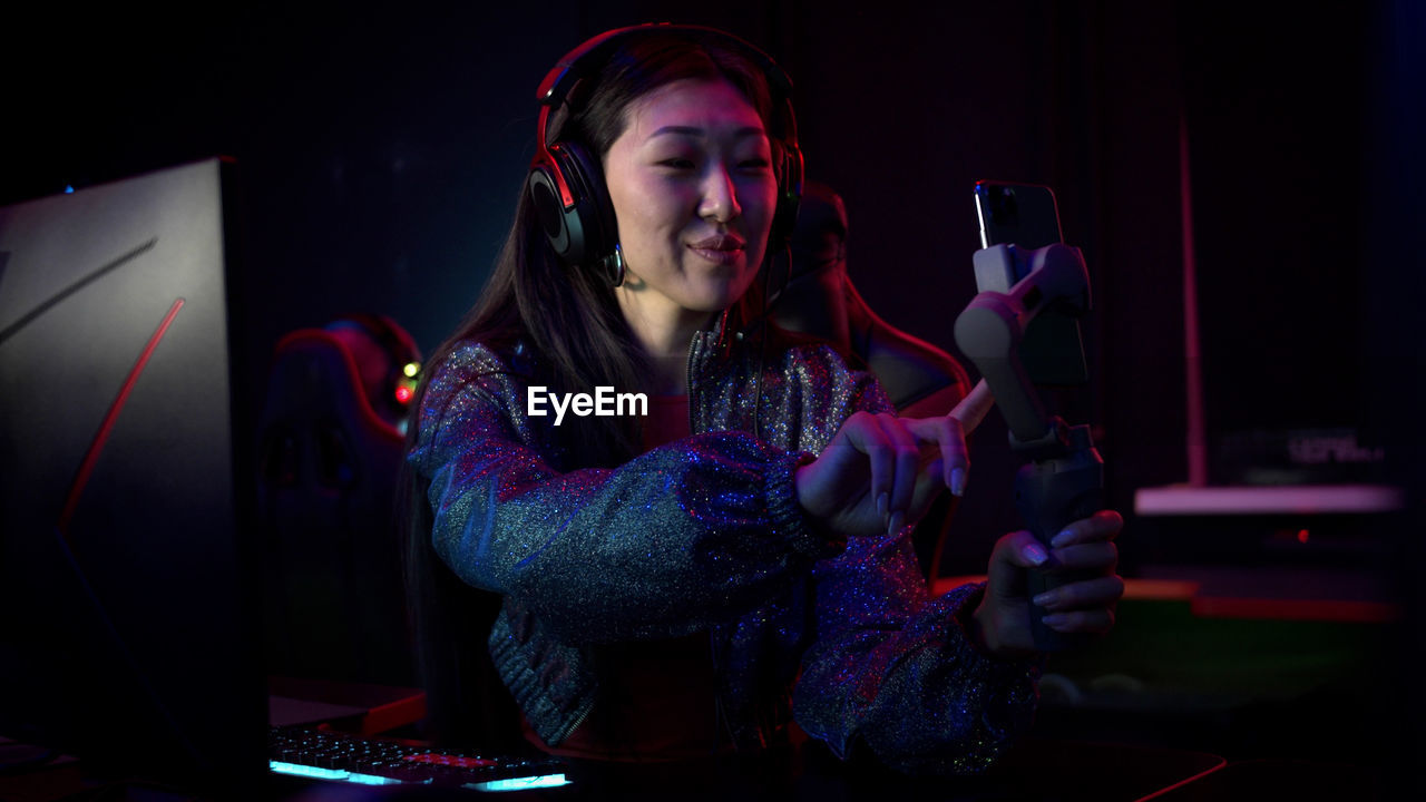 Smiling woman vlogging while sitting at internet cafe