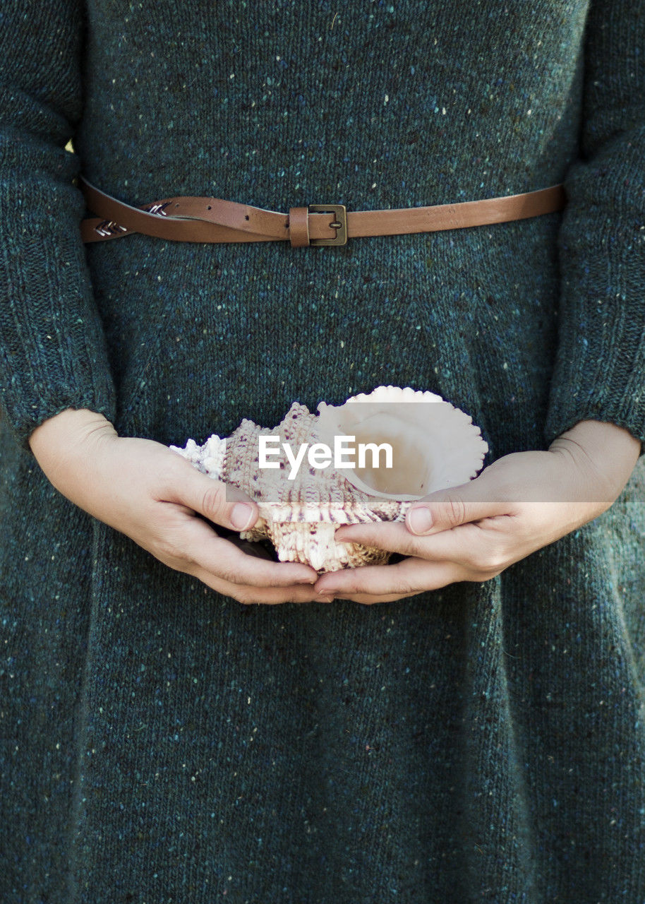 Midsection of woman holding seashell