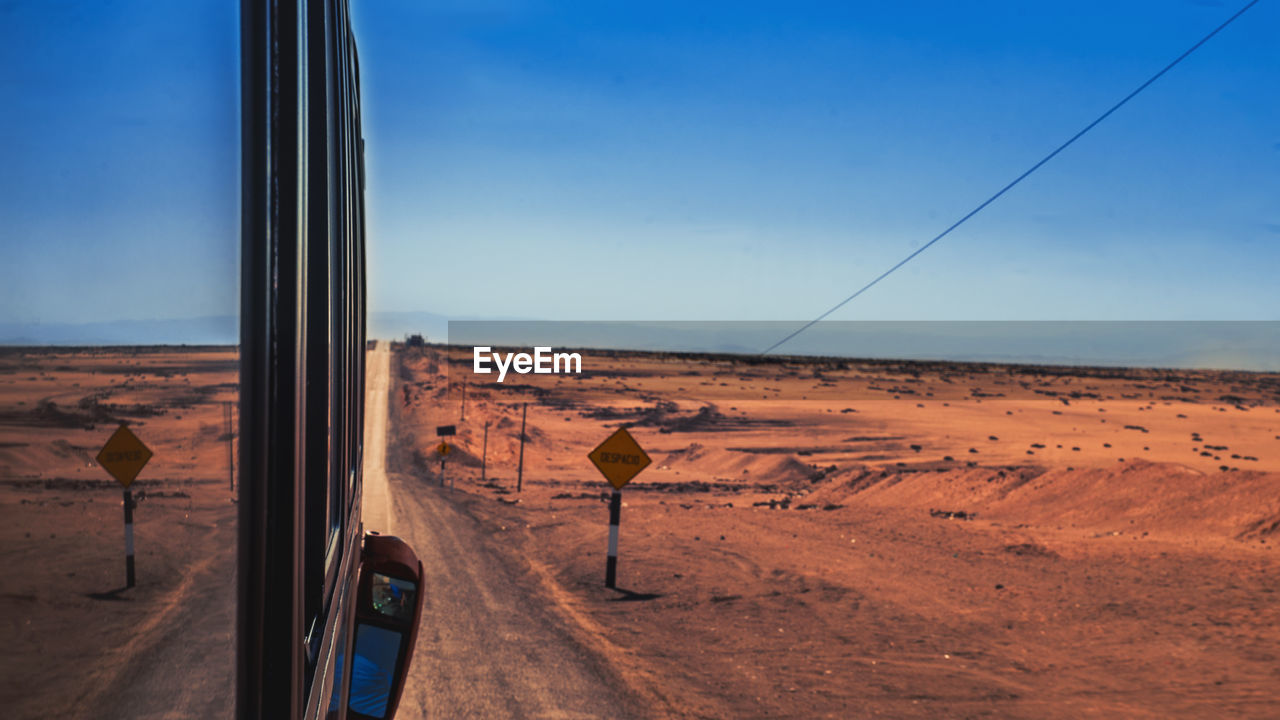 Cropped image of vehicle at desert against clear sky
