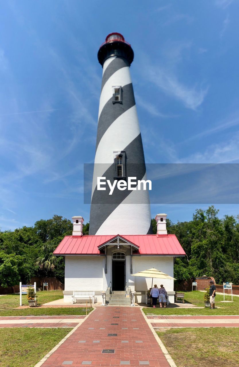 VIEW OF LIGHTHOUSE BY BUILDING AGAINST SKY