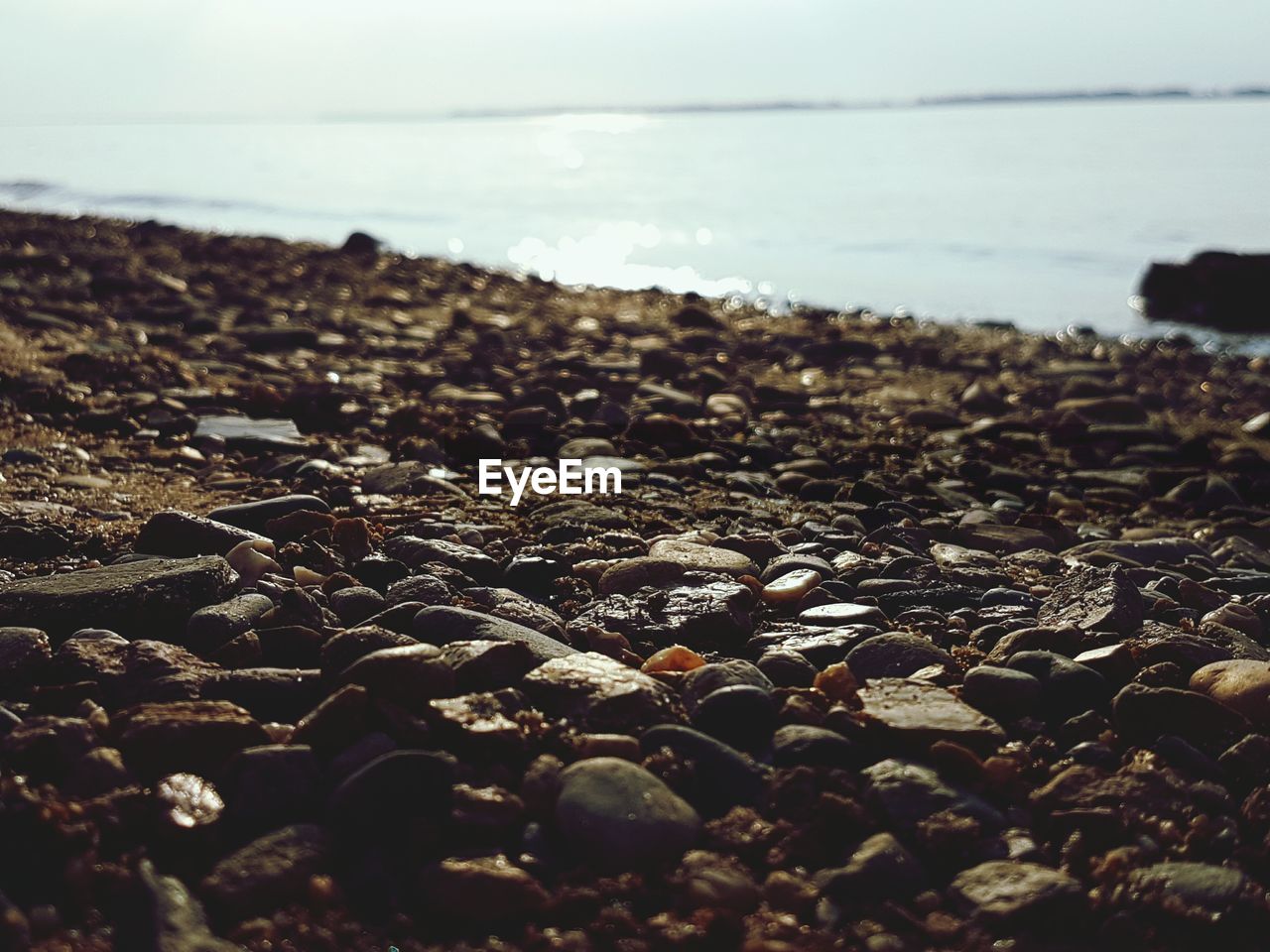 Close-up of pebbles with sea in background