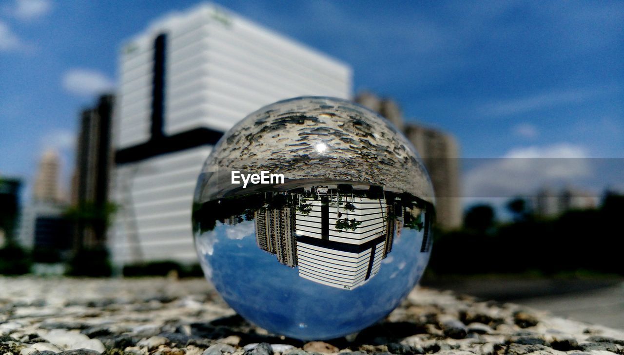 Buildings reflecting on crystal ball in city