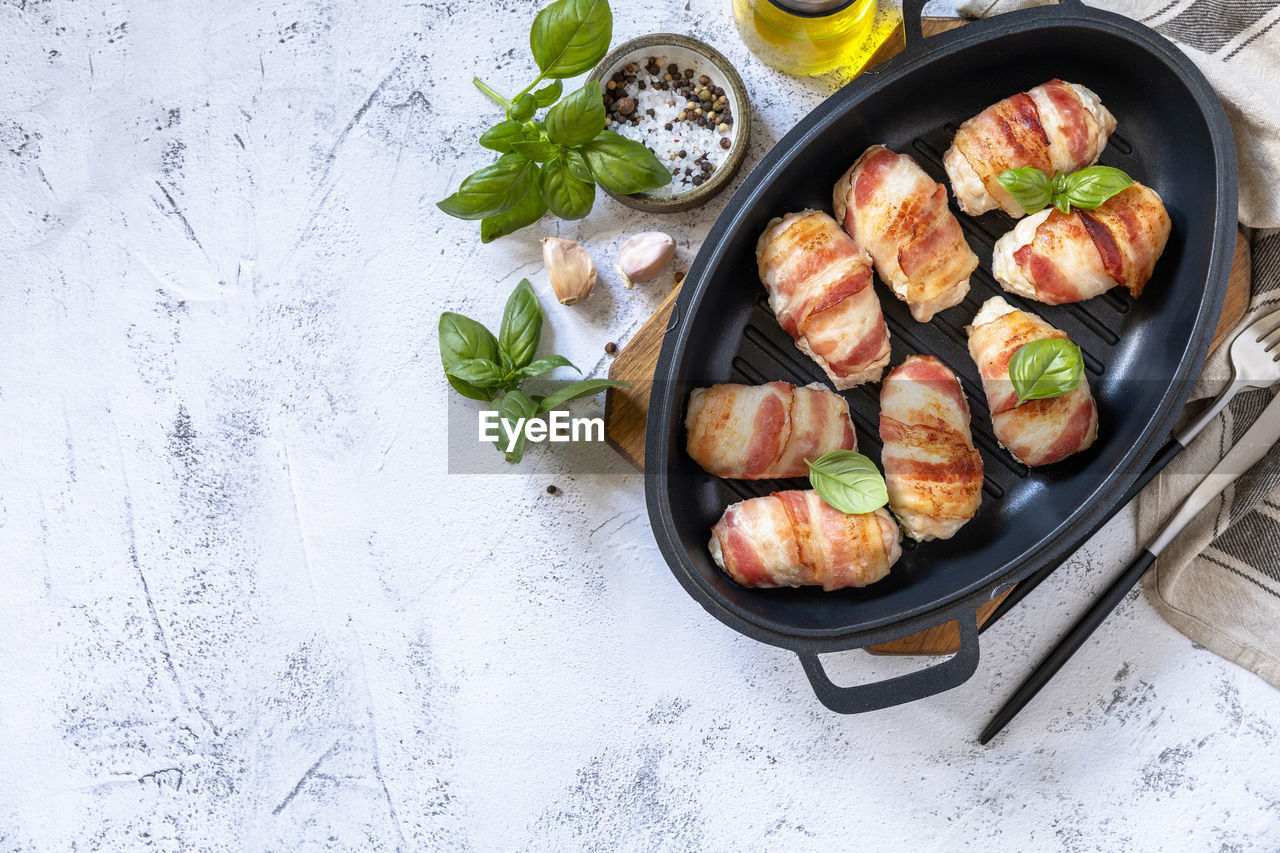 A festive dish. baked chicken fillet with ricotta in bacon on a stone table top. top view flat lay. 