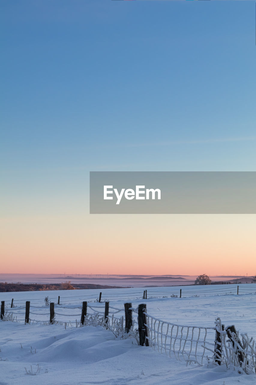 SCENIC VIEW OF SNOW COVERED FIELD AGAINST CLEAR SKY