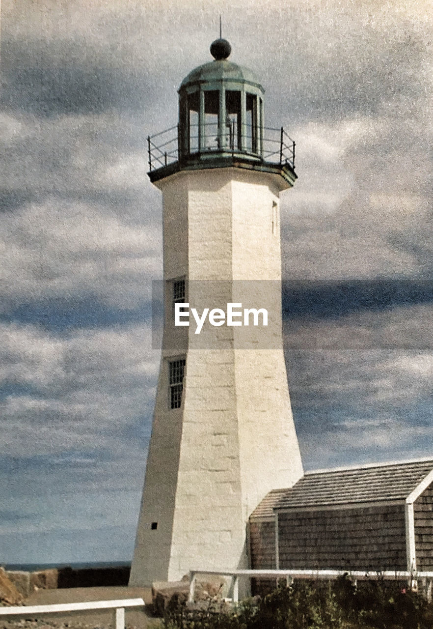 Low angle view of old scituate light against cloudy sky