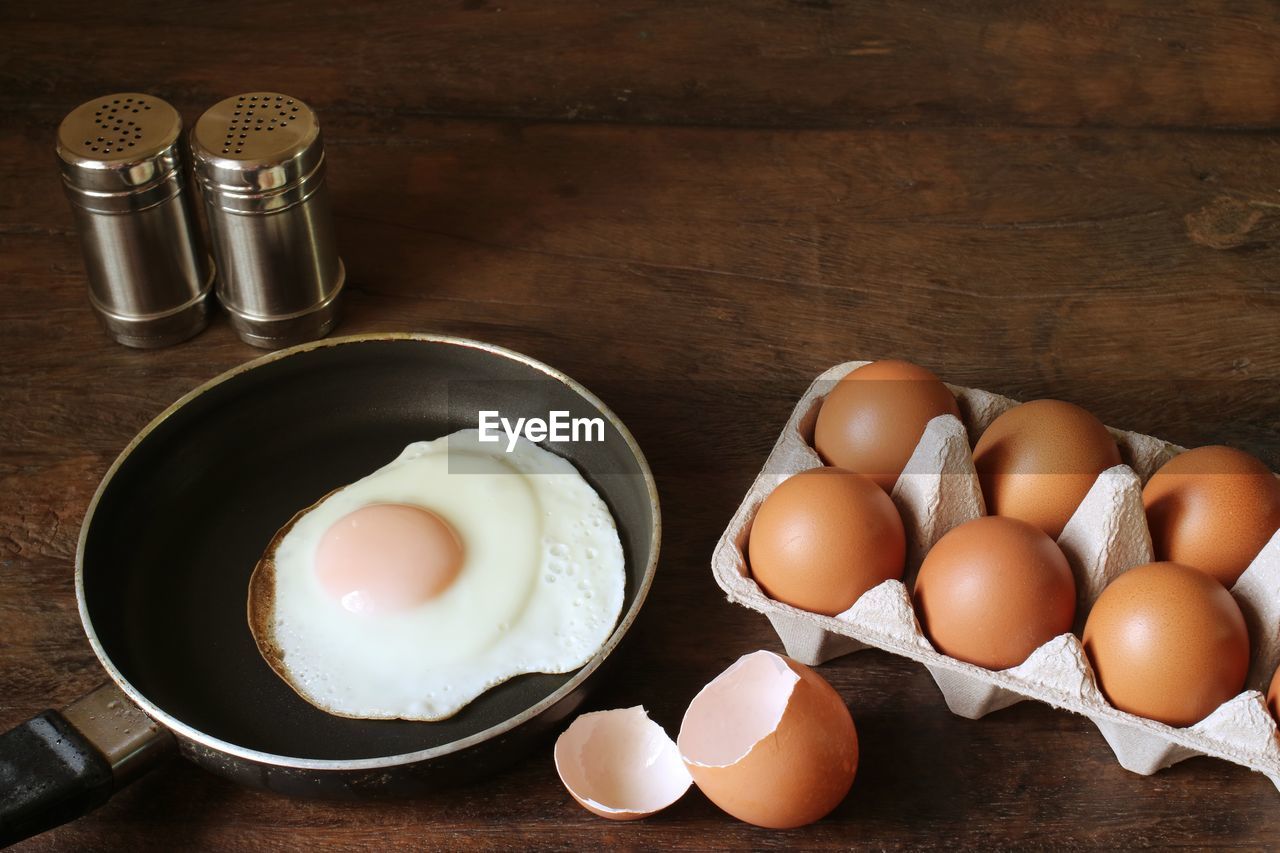 Eggs and fried egg on the wooden table.