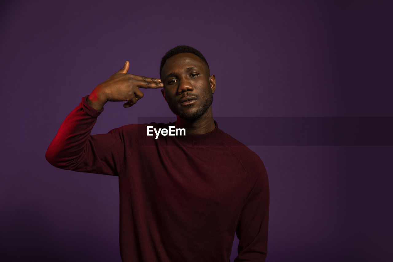 PORTRAIT OF MAN STANDING AGAINST COLORED BACKGROUND