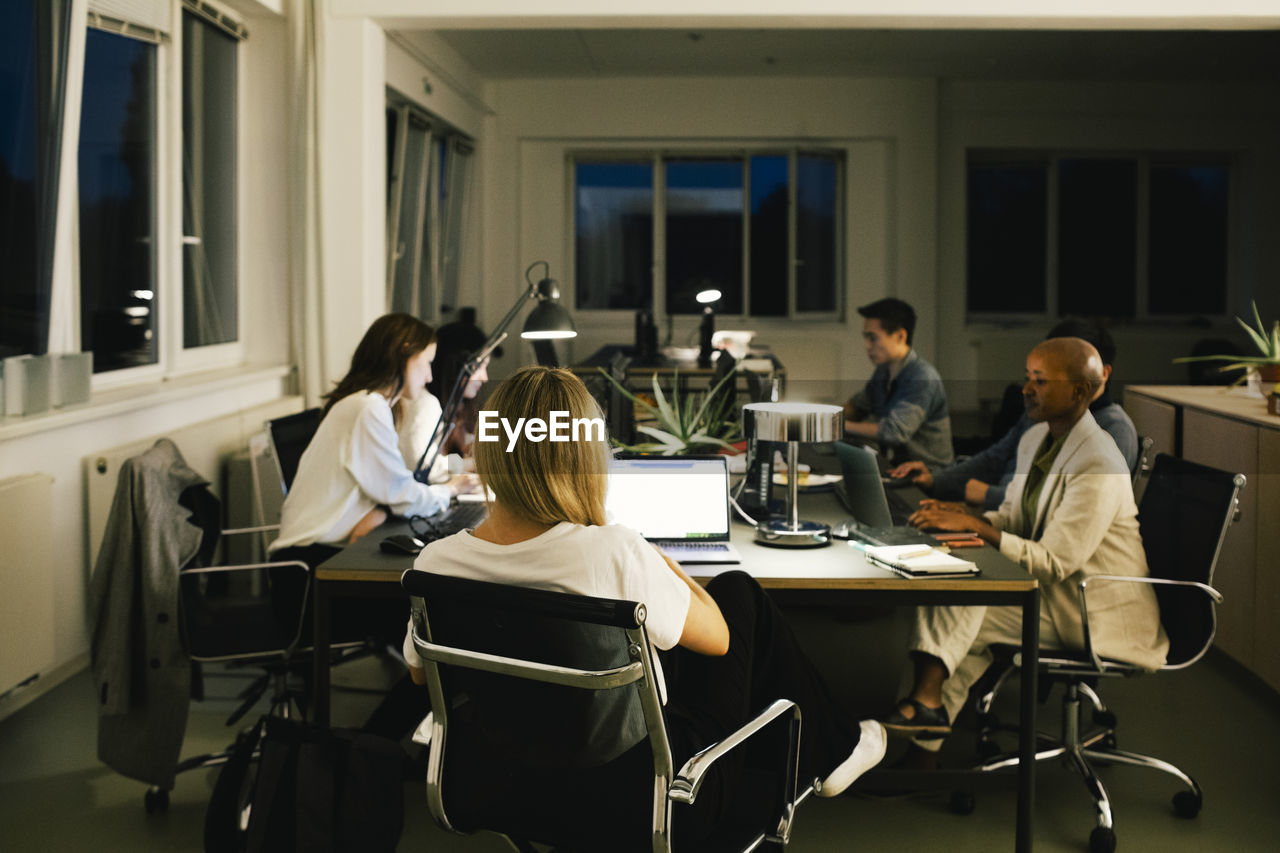 Business colleagues working late while sitting at desk in office