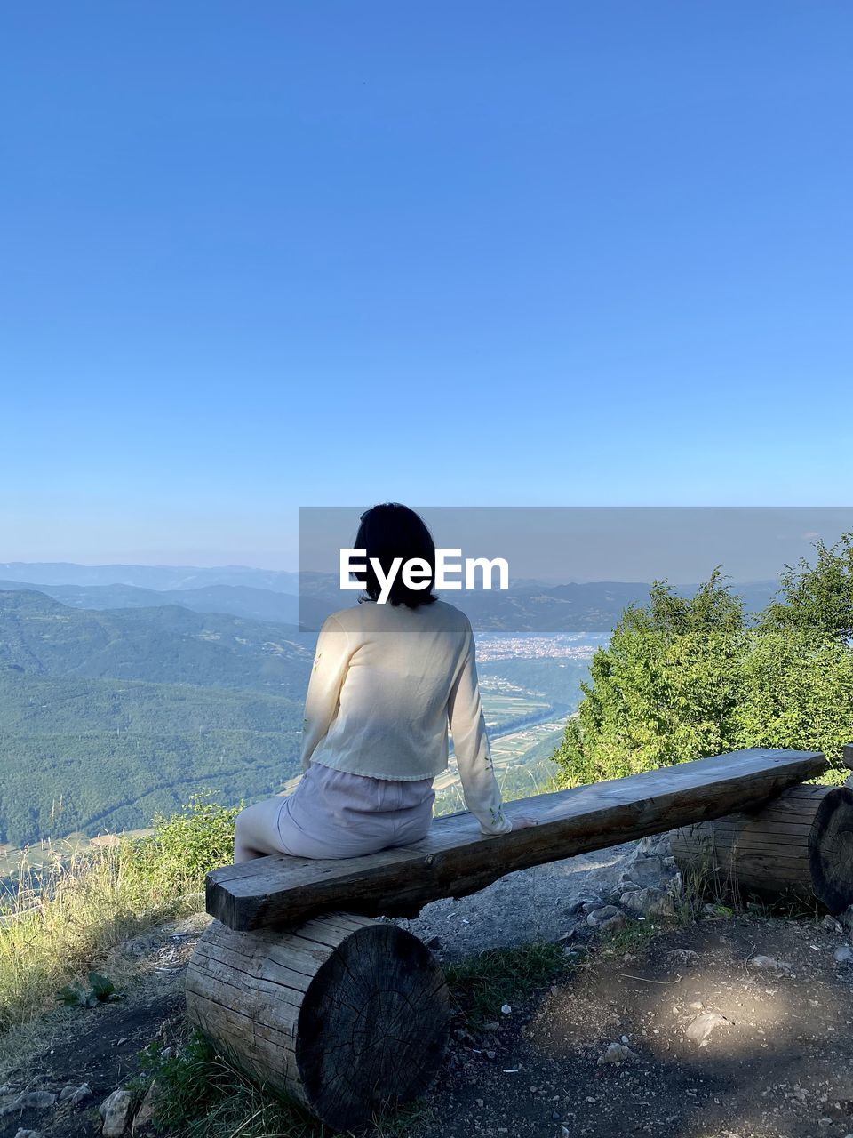 REAR VIEW OF MAN SITTING AGAINST CLEAR BLUE SKY