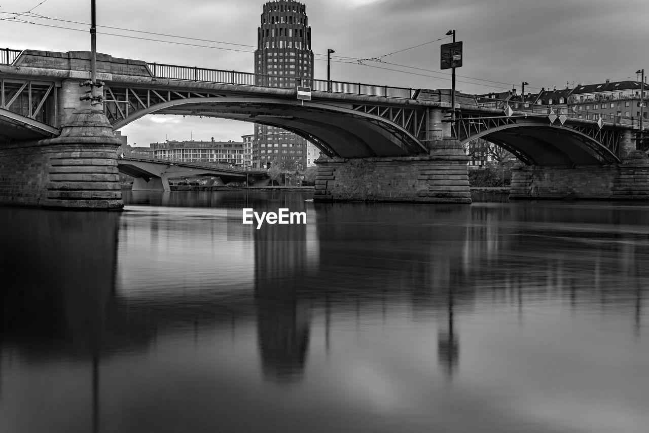 bridge over river in city against sky