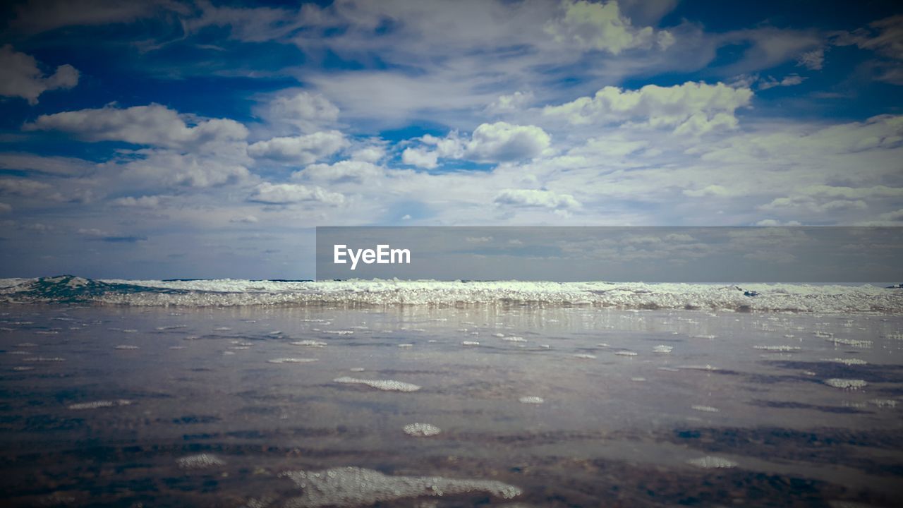 VIEW OF CALM BEACH AGAINST CLOUDS