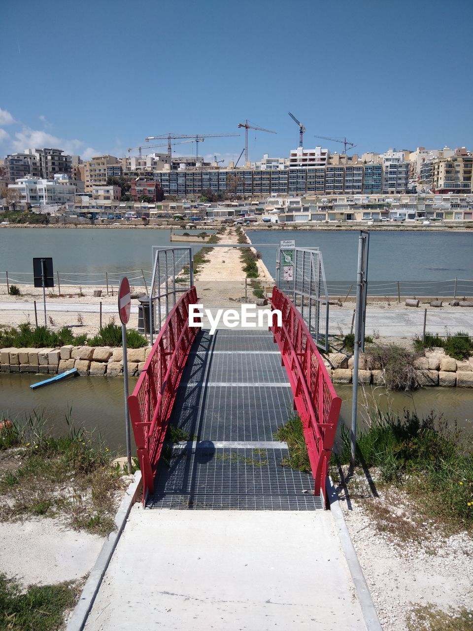 Bridge near seaside against buildings in city against sky