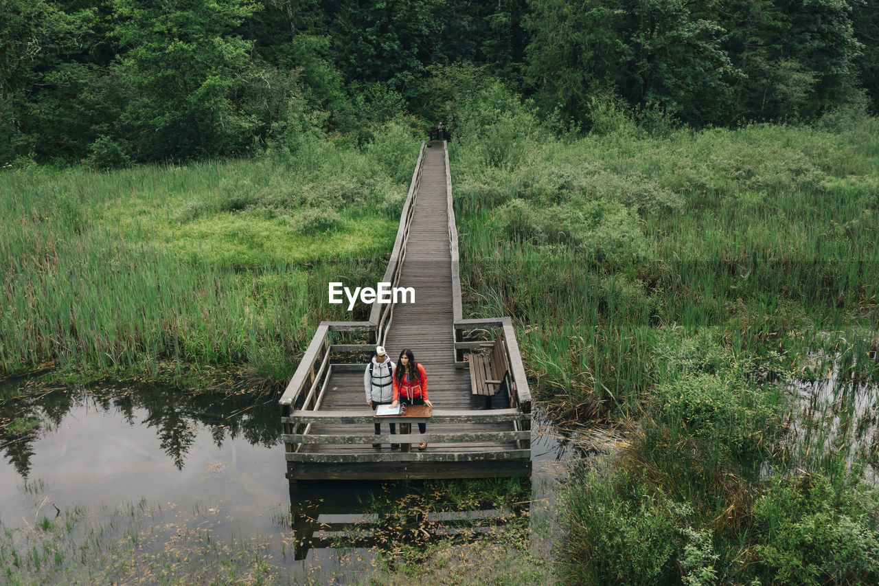 A young couple enjoys a hike on a boardwalk in the pacific northwest.