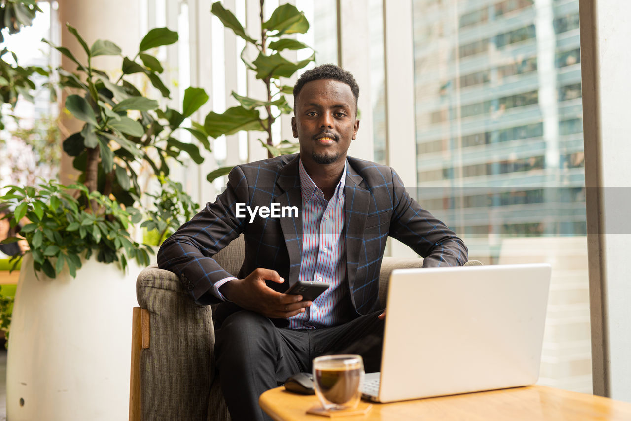 portrait of young man using digital tablet while sitting on chair at home