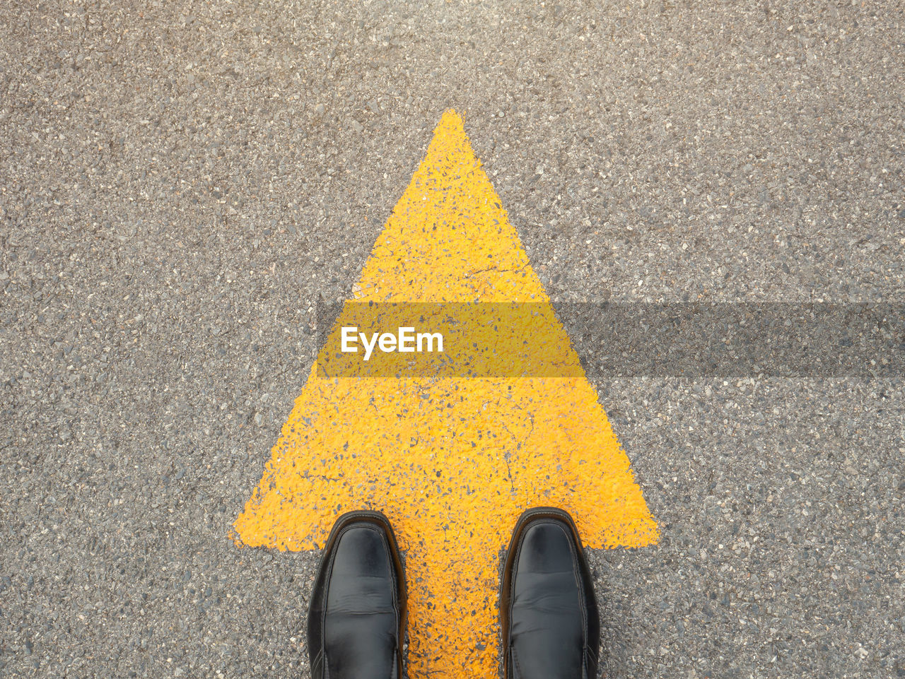 Low section of man standing on yellow arrow symbol