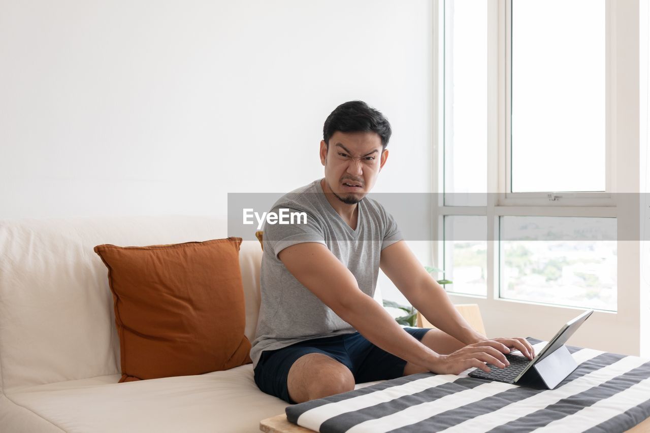 side view of young woman using laptop while sitting on sofa at home