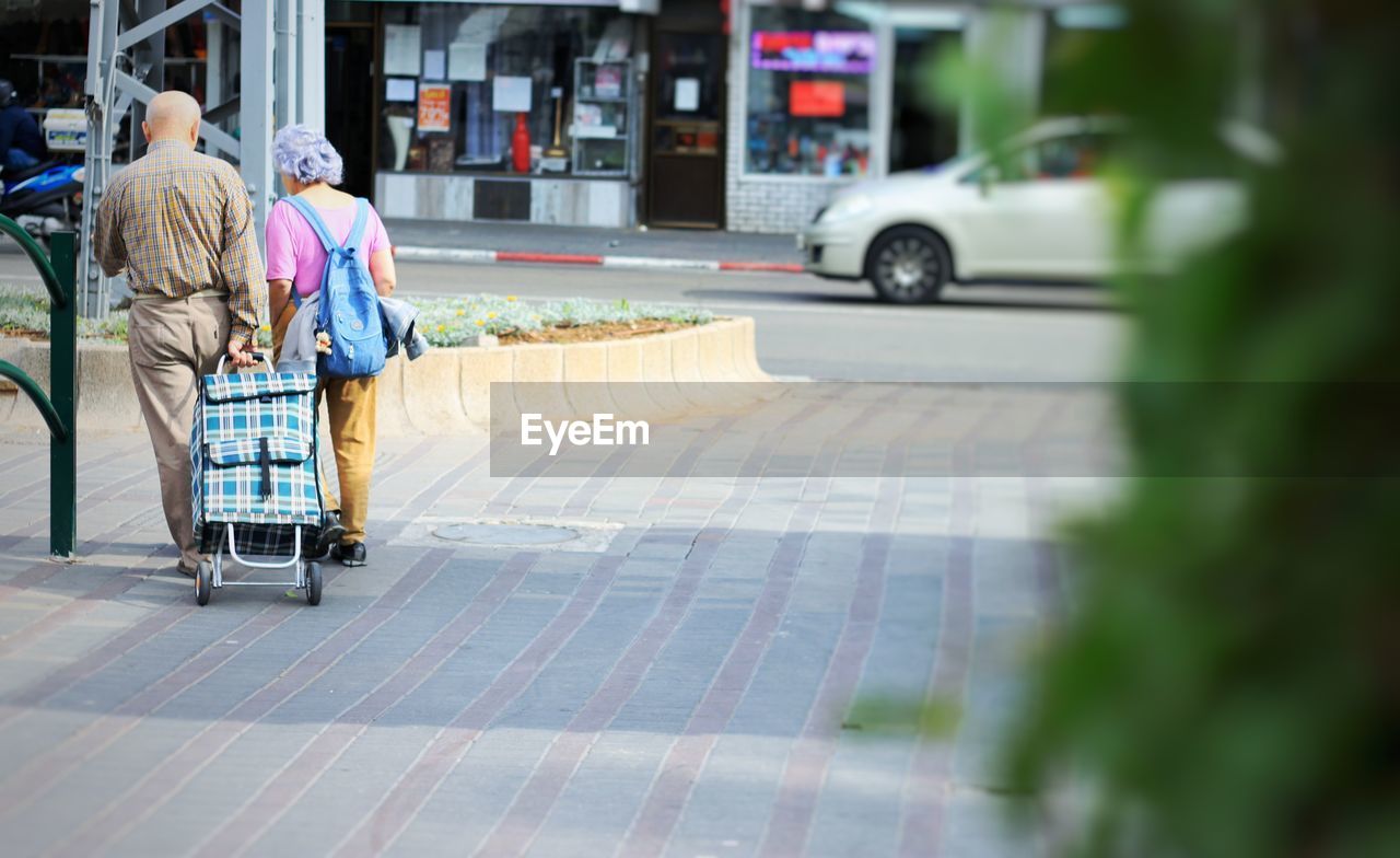 Rear view of people walking on street in city