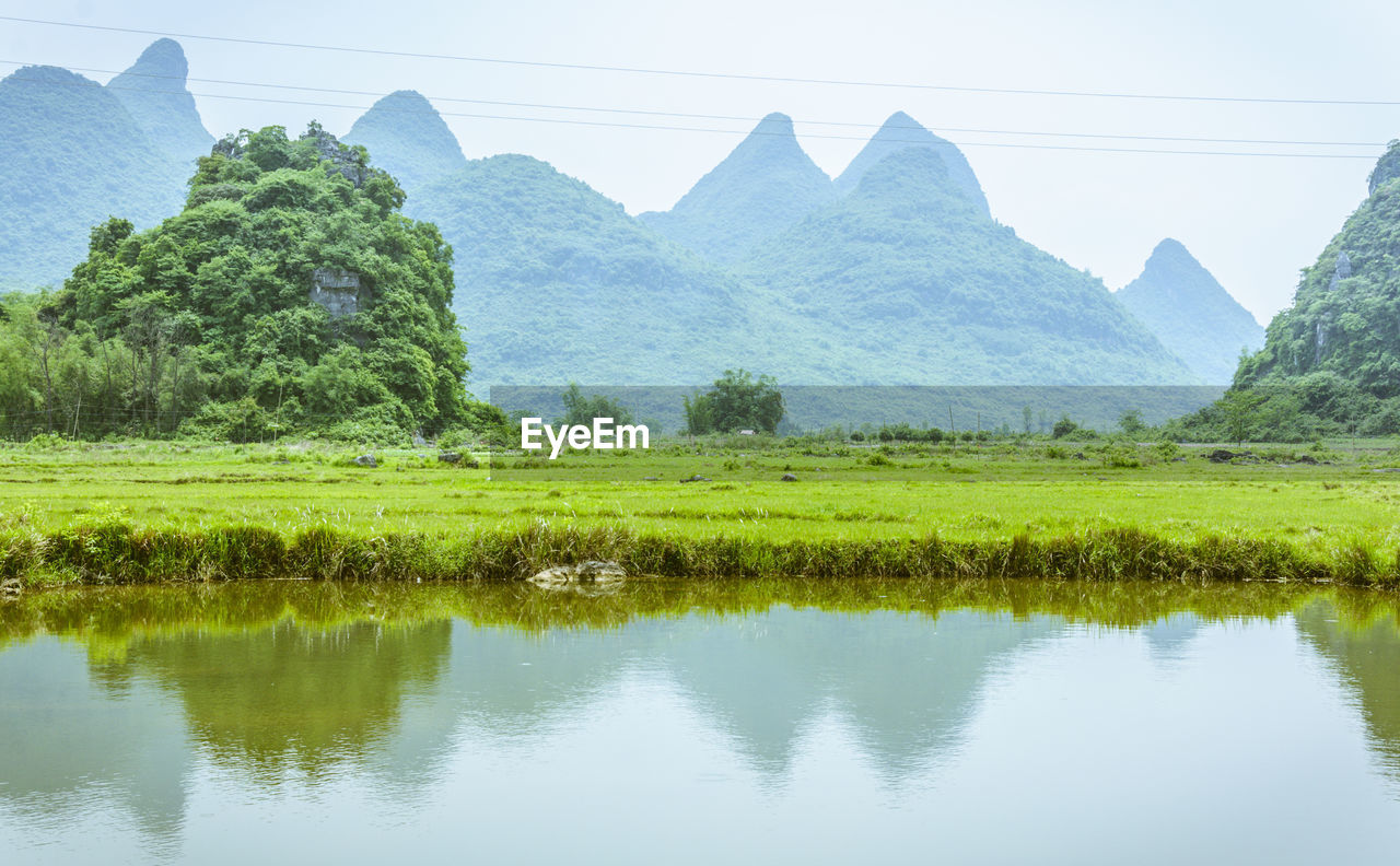 Scenic view of river by mountains against clear sky