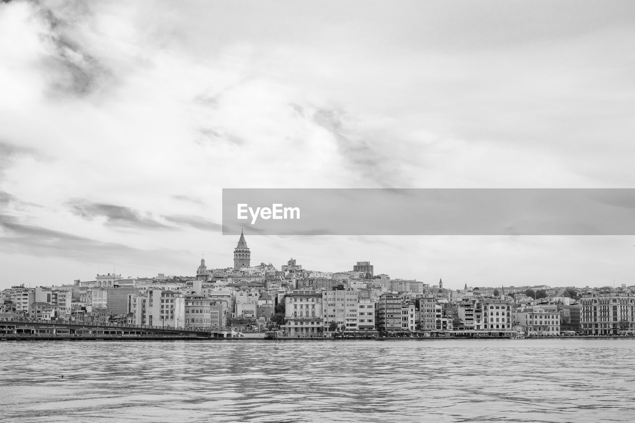 Cityscape in front of river against sky