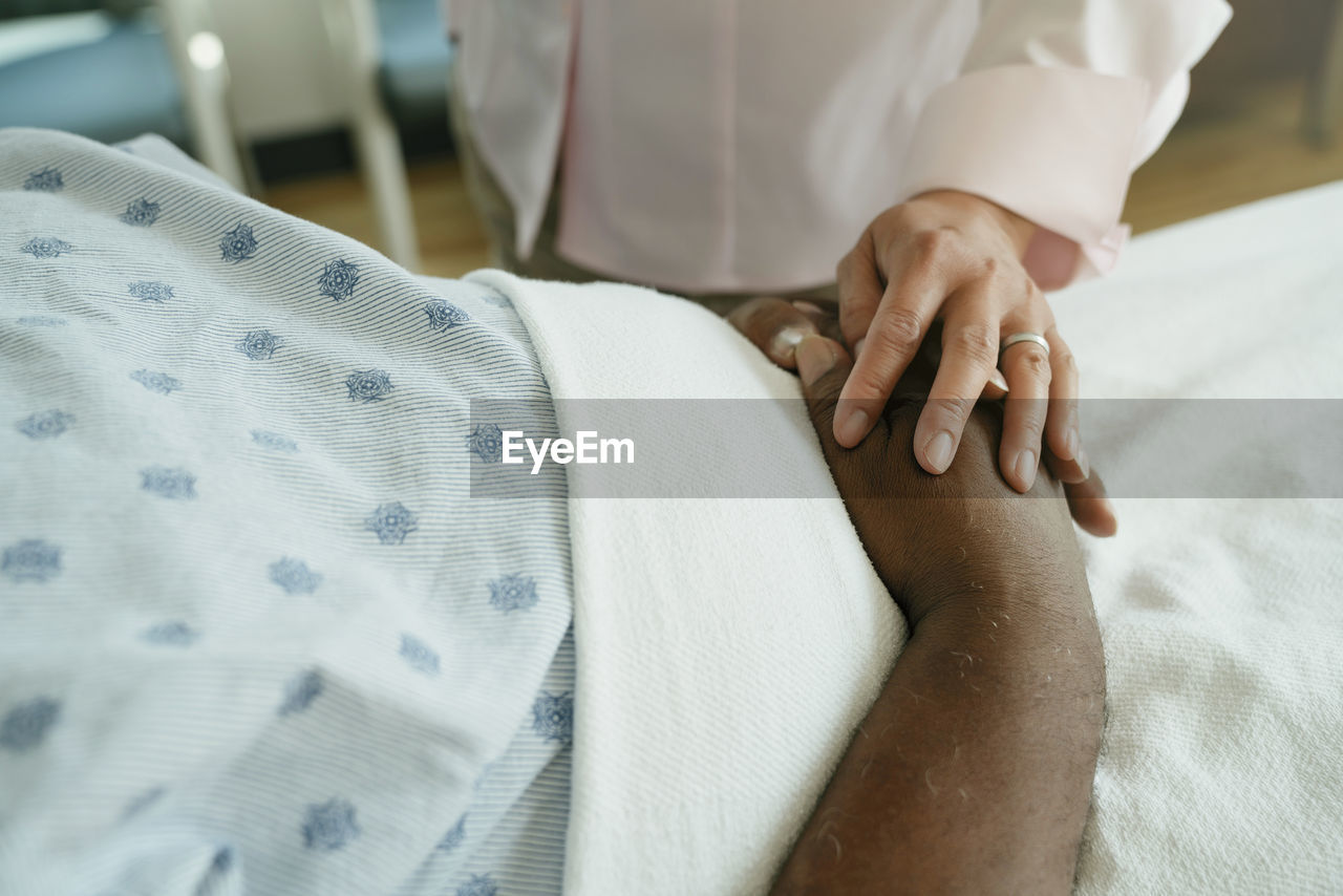 Close-up of doctor comforting senior patient in hospital ward