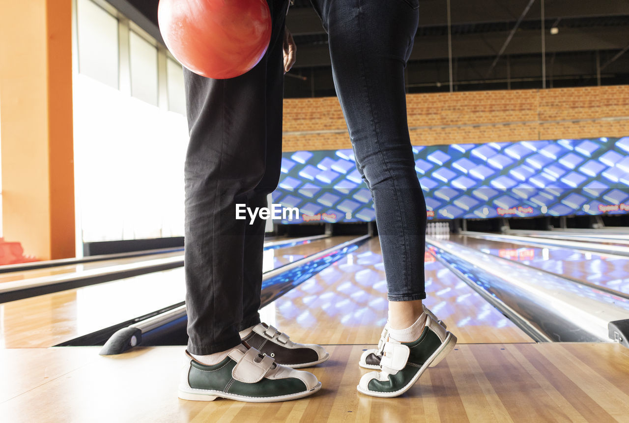 Woman standing on tiptoe with friend at bowling alley