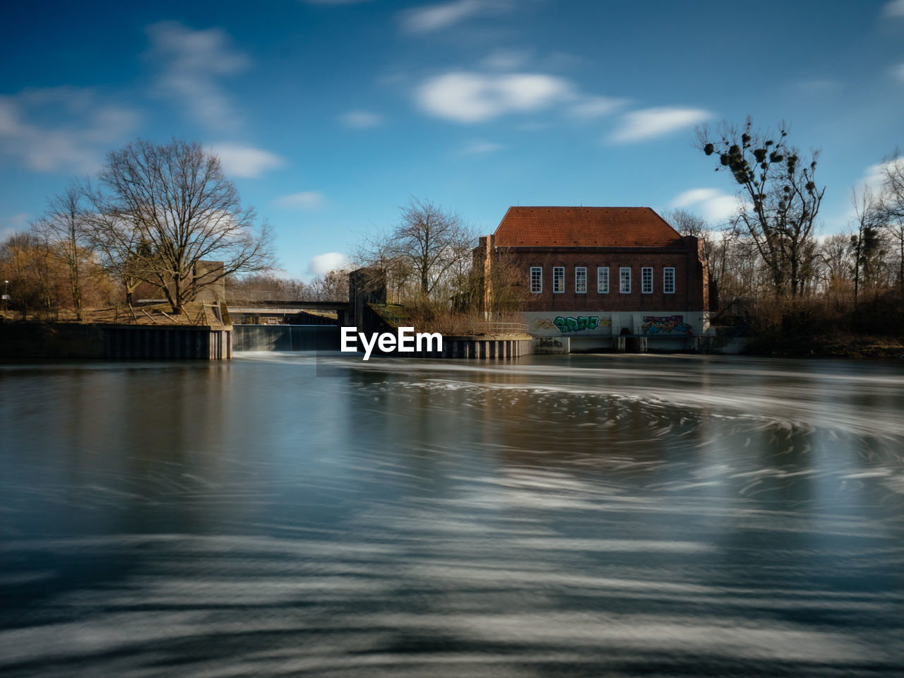 River against bare trees and building