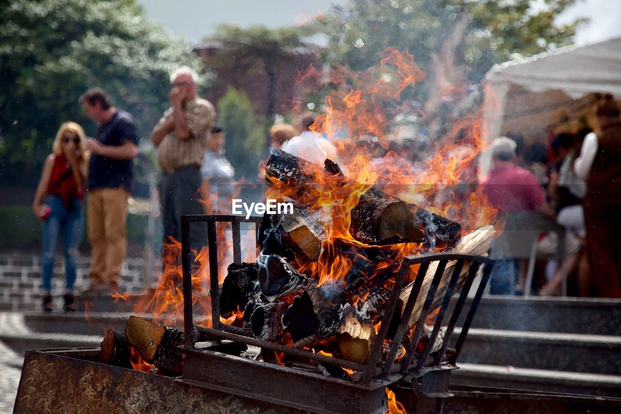 Close-up of barbecue grill with people in background