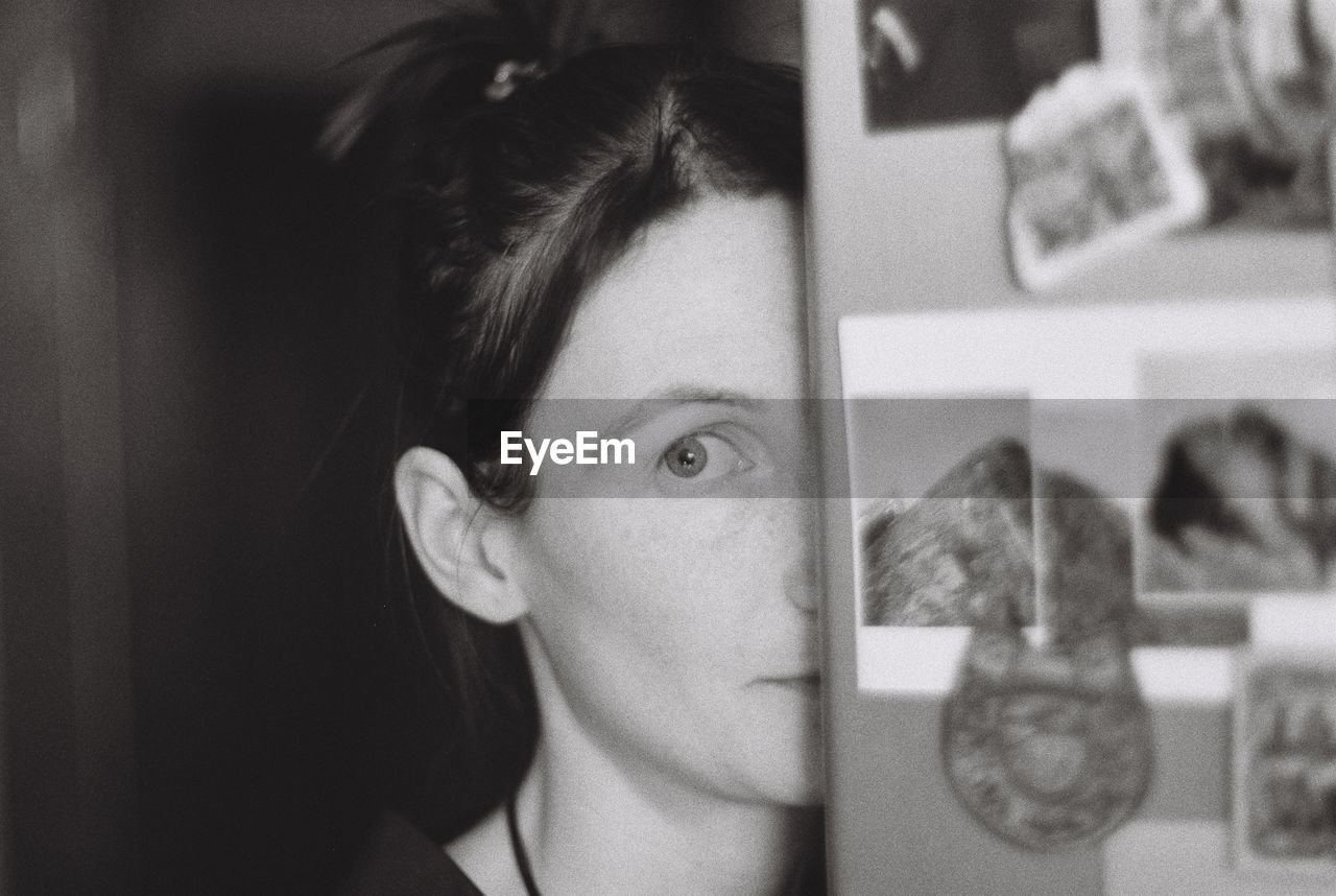 Close-up portrait of woman peeking by wall