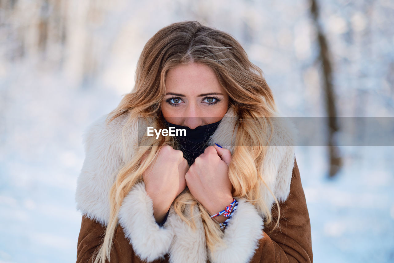 Portrait of young woman wearing warm clothing standing in forest