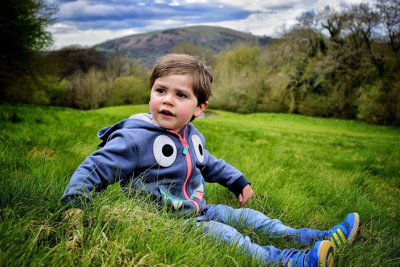 Full length of boy relaxing on grassy field