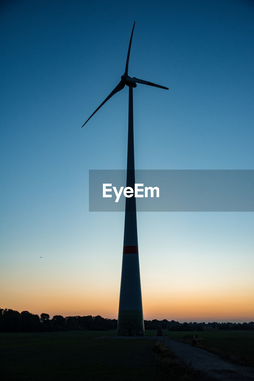 Low angle view of wind turbine against sky during sunset