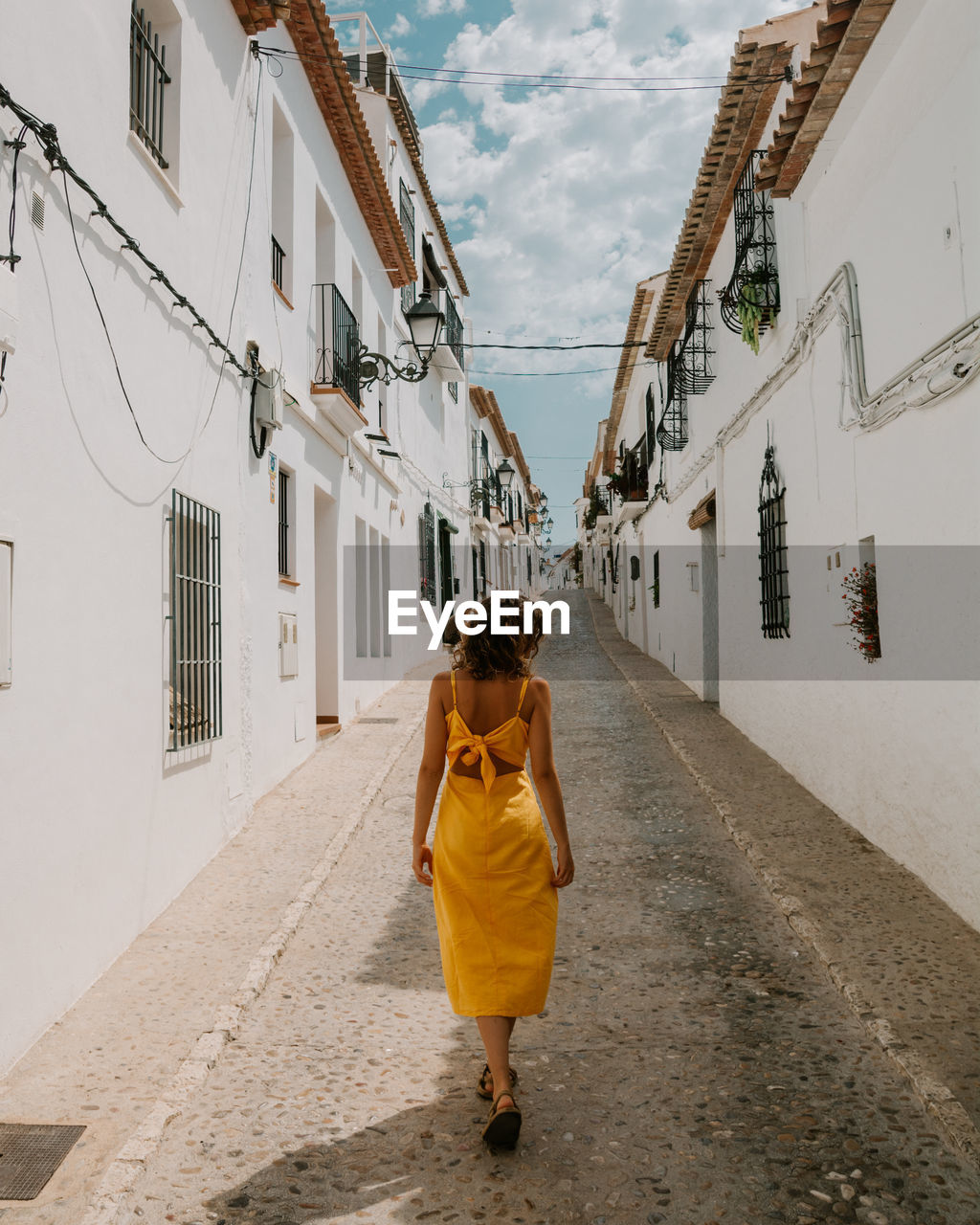 Woman walking on footpath in an alley 