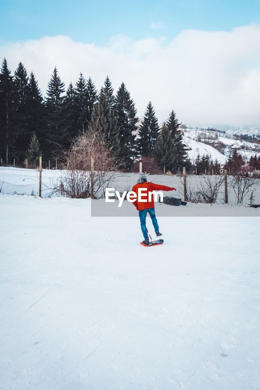 WOMAN ON SNOW COVERED FIELD AGAINST TREES AND MOUNTAINS