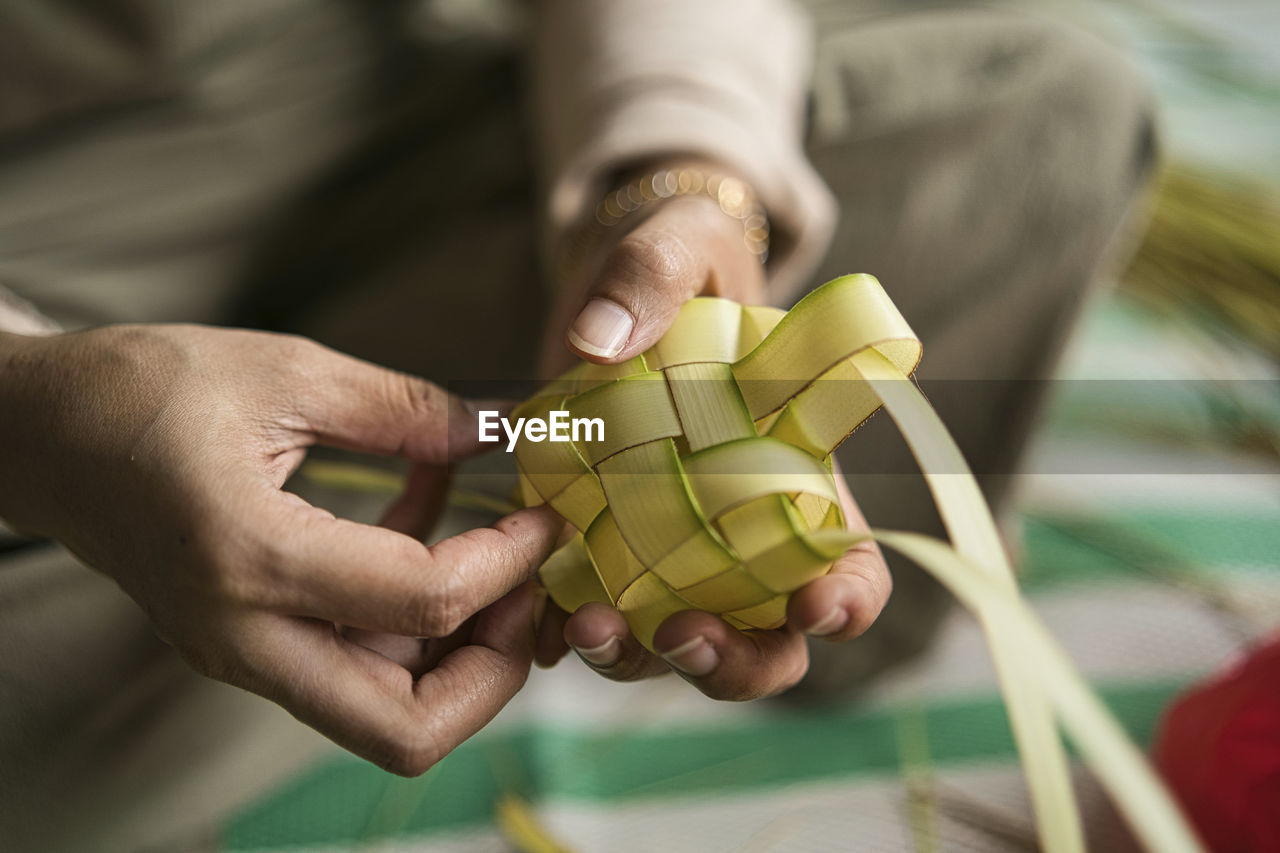 Weaving the coconut leaves making the ketupat, a traditional malay cuisine for the eid celebration.