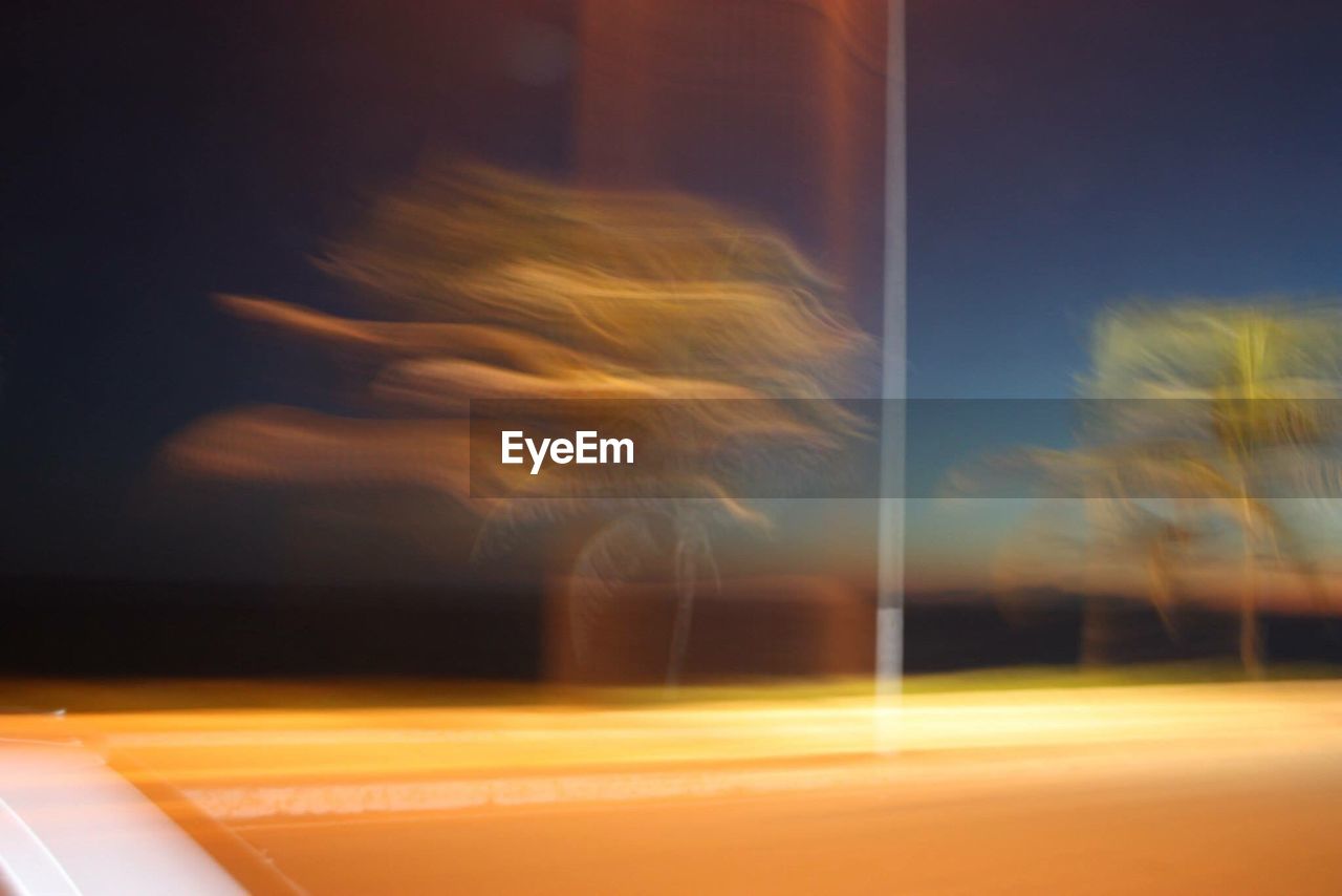 Blurred motion of trees seen through vehicle at dusk