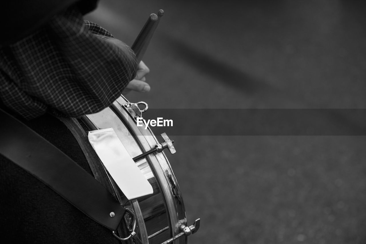 Cropped hand playing drum on street