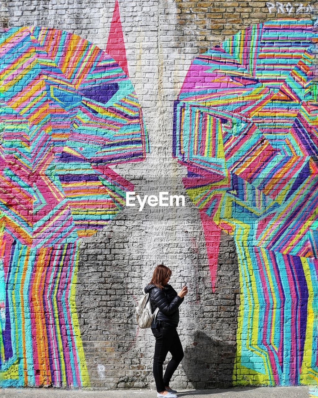 REAR VIEW OF WOMAN STANDING AGAINST MULTI COLORED WALL