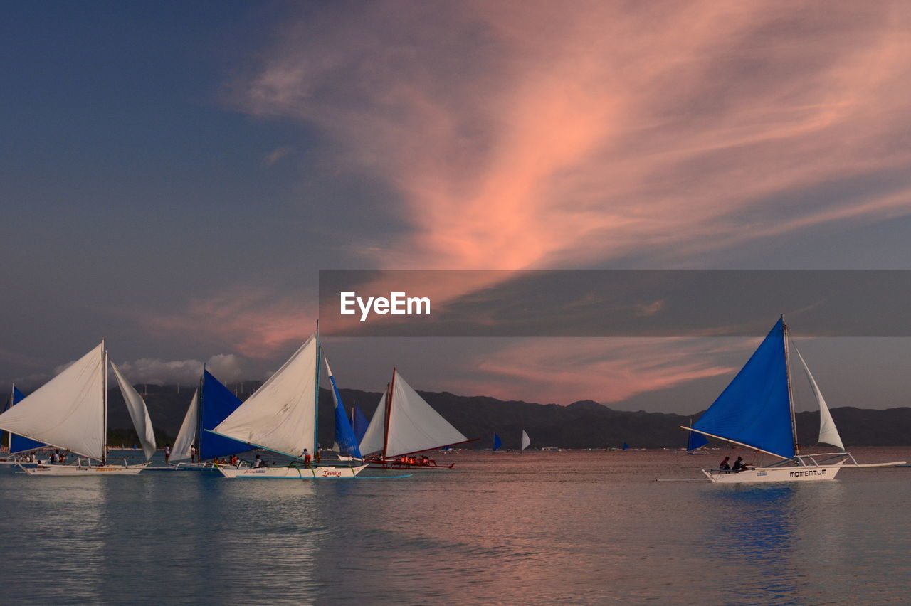 SAILBOAT SAILING ON SEA AGAINST SKY DURING SUNSET