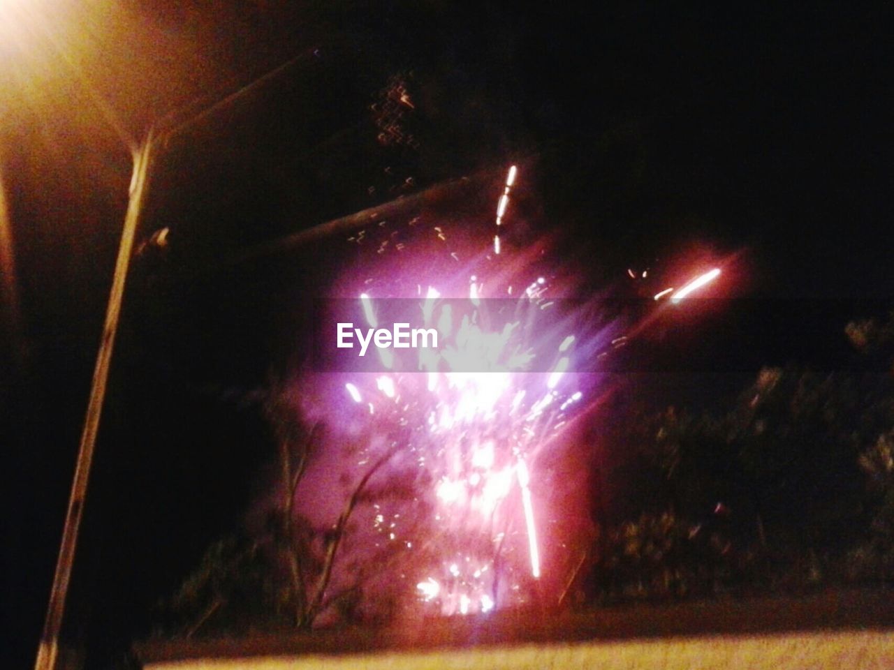 LOW ANGLE VIEW OF ILLUMINATED FIREWORK DISPLAY AT NIGHT