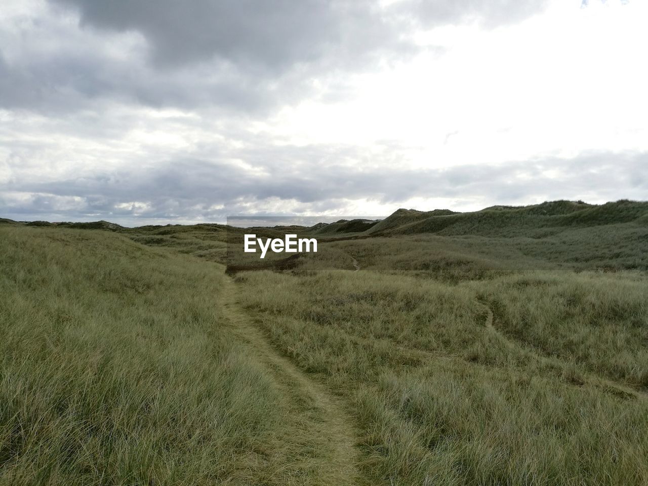 Scenic view of grassy field against cloudy sky