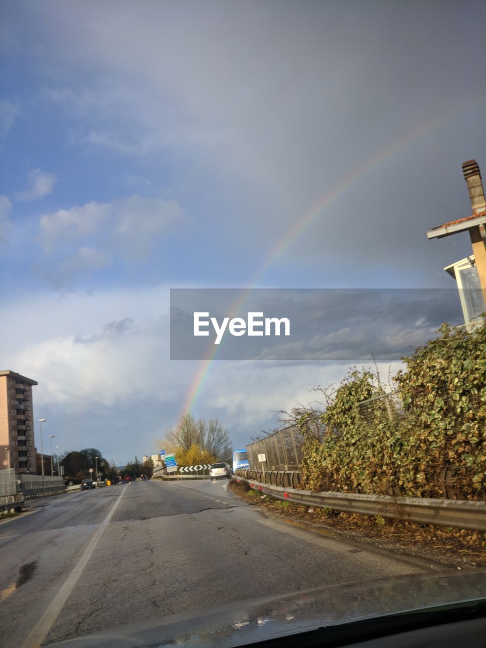 Rainbow over road in city against sky