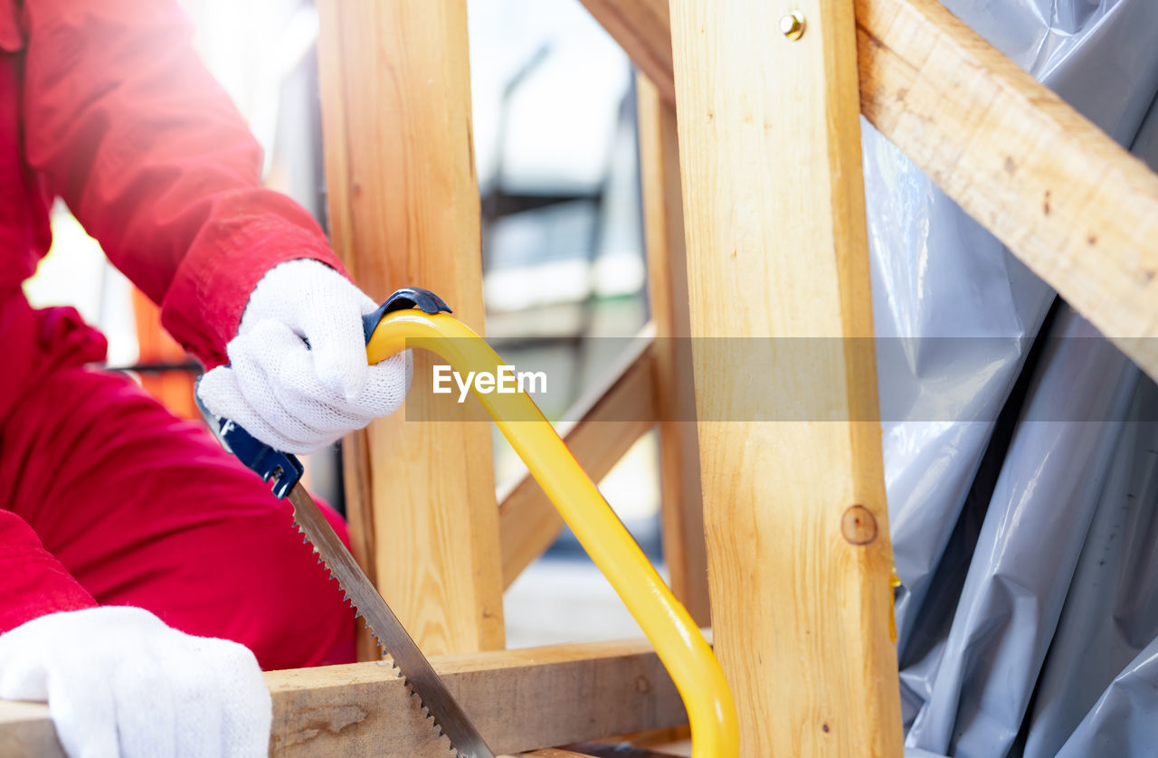 A worker is sawing wood to assemble a crate for moving an industrial machine. a woman in coveralls