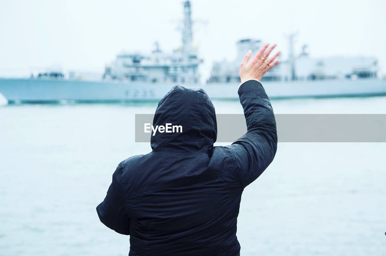 Rear view of person waving at ship